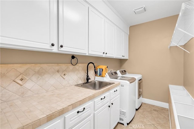 clothes washing area featuring washer and clothes dryer, light tile patterned flooring, cabinets, and sink