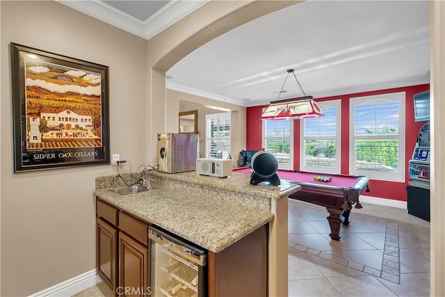 interior space featuring hanging light fixtures, crown molding, sink, light tile patterned floors, and beverage cooler