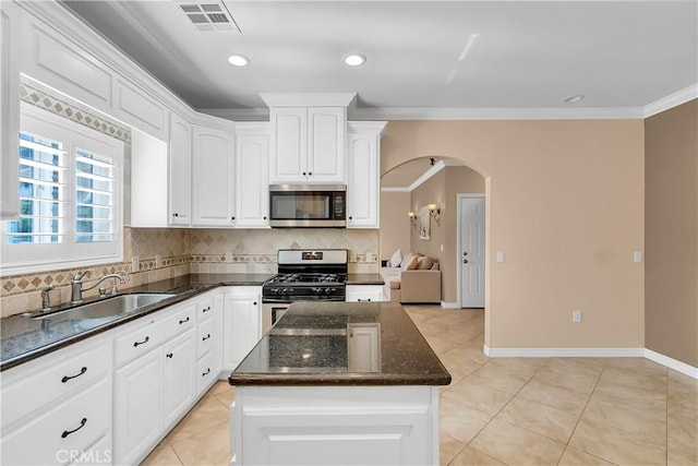 kitchen with tasteful backsplash, stainless steel appliances, sink, a center island, and white cabinetry