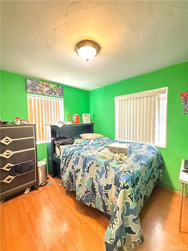 bedroom with multiple windows and hardwood / wood-style floors