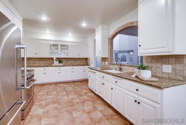 kitchen featuring stone counters, white cabinetry, sink, decorative backsplash, and appliances with stainless steel finishes