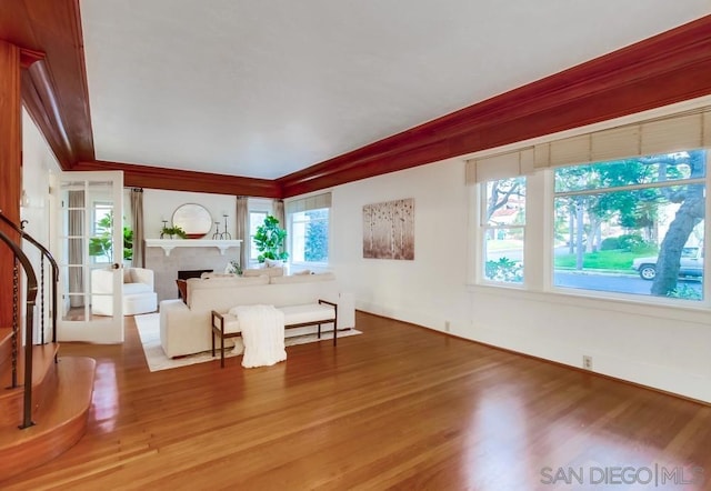 unfurnished living room with wood-type flooring and ornamental molding