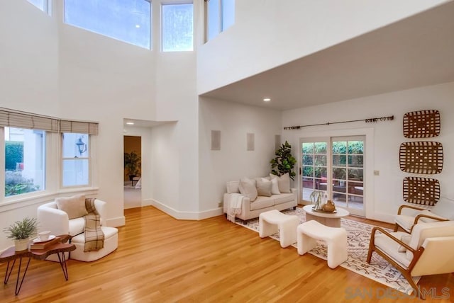 living room with a towering ceiling and light wood-type flooring