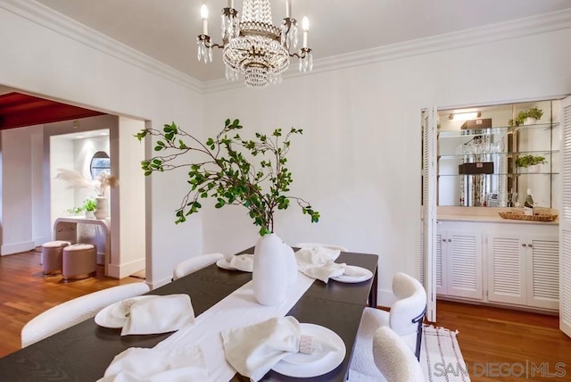 dining room with hardwood / wood-style floors, an inviting chandelier, and ornamental molding