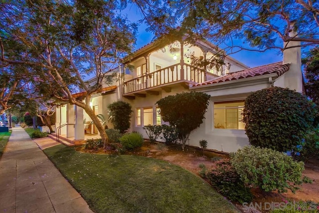 view of front of house with a front yard and a balcony