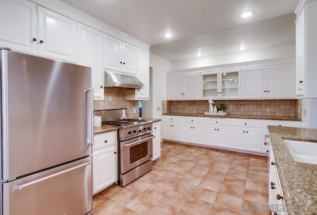 kitchen featuring sink, decorative backsplash, appliances with stainless steel finishes, light stone counters, and white cabinetry