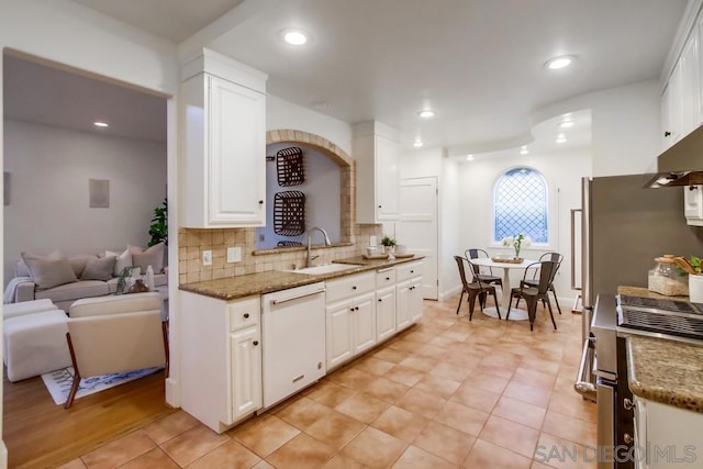 kitchen with white cabinets, white dishwasher, sink, tasteful backsplash, and stainless steel range oven