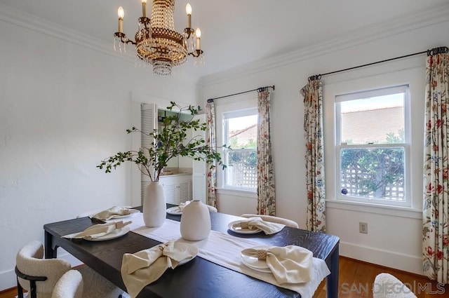 dining space with dark hardwood / wood-style flooring, an inviting chandelier, and ornamental molding