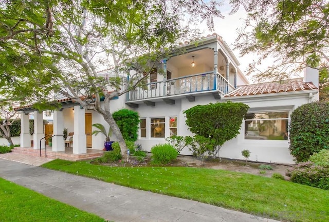 view of front of house with a balcony and a front lawn