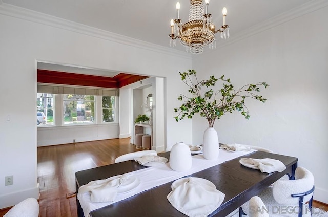 dining room with dark hardwood / wood-style flooring, crown molding, and a chandelier