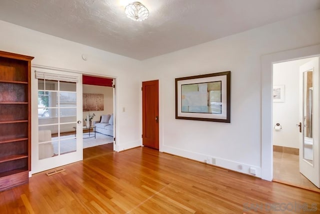 empty room featuring french doors, a textured ceiling, and hardwood / wood-style flooring