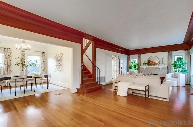 living room with hardwood / wood-style floors, an inviting chandelier, and ornamental molding