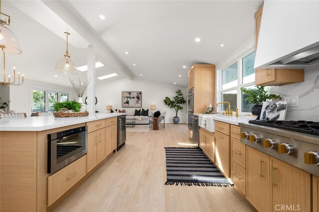 kitchen with stainless steel gas stovetop, custom exhaust hood, lofted ceiling with beams, light brown cabinetry, and decorative light fixtures