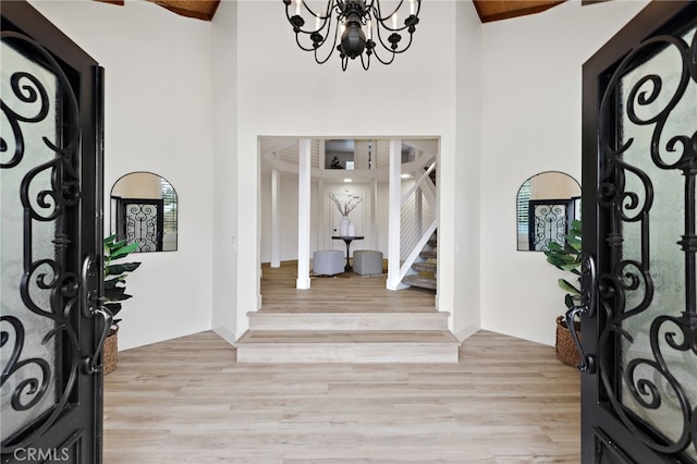 entrance foyer with high vaulted ceiling, light hardwood / wood-style floors, and an inviting chandelier