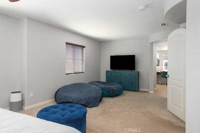 bedroom featuring light carpet and ensuite bath