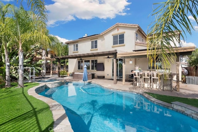 back of property with a pergola, a pool with hot tub, exterior bar, ceiling fan, and a patio