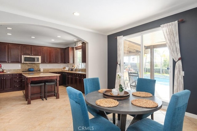 tiled dining area with ornamental molding and a wealth of natural light