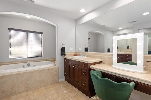 bathroom with tile patterned floors, vanity, and a relaxing tiled tub