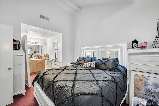 bedroom with dark colored carpet, beam ceiling, connected bathroom, and high vaulted ceiling