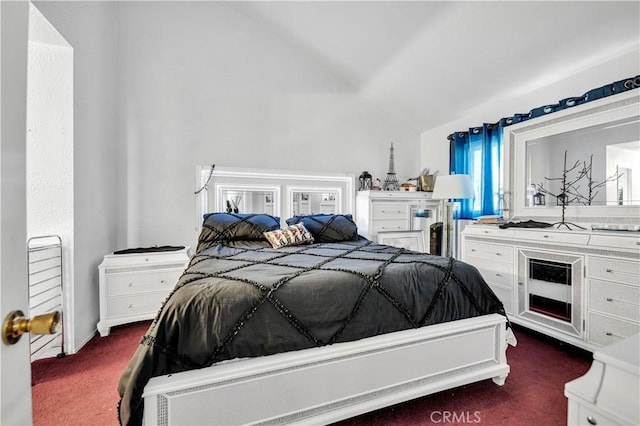 bedroom with lofted ceiling and dark colored carpet