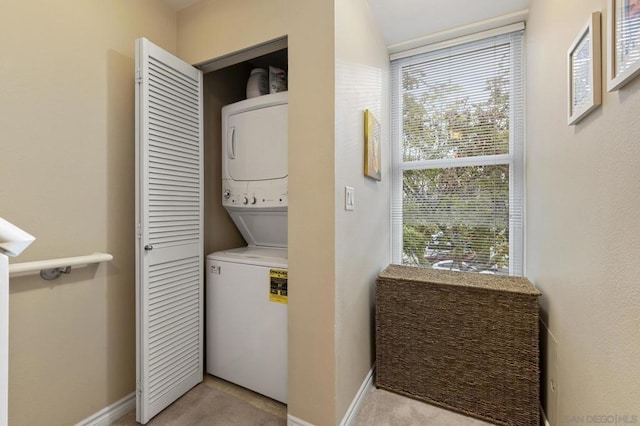 laundry room featuring light carpet, stacked washing maching and dryer, and a wealth of natural light