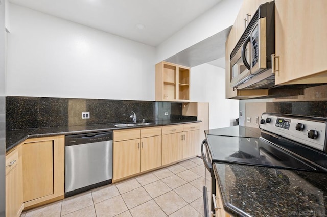 kitchen featuring sink, dark stone countertops, light tile patterned floors, light brown cabinetry, and appliances with stainless steel finishes