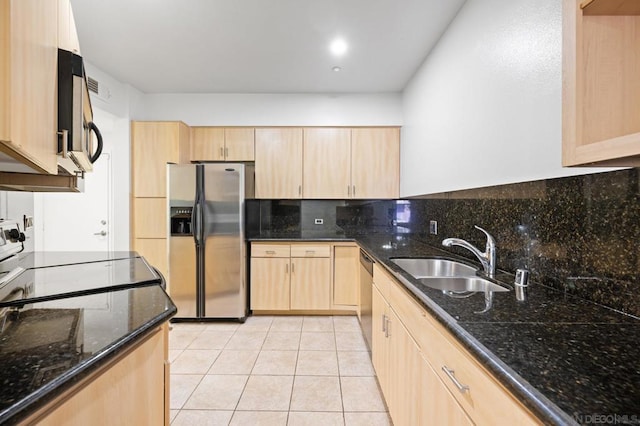 kitchen featuring light brown cabinets, sink, stainless steel appliances, dark stone countertops, and light tile patterned floors