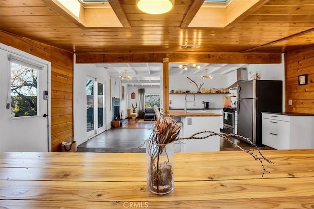 dining area featuring a skylight, wooden walls, french doors, and wooden ceiling