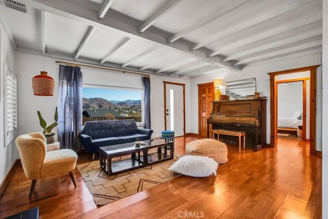 living area with beamed ceiling and hardwood / wood-style floors