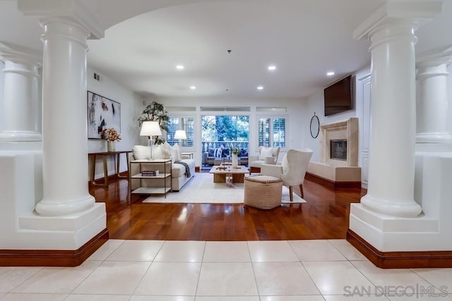 living room featuring decorative columns, light tile patterned floors, and a high end fireplace