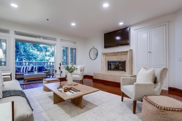 living room with a tile fireplace and light hardwood / wood-style flooring