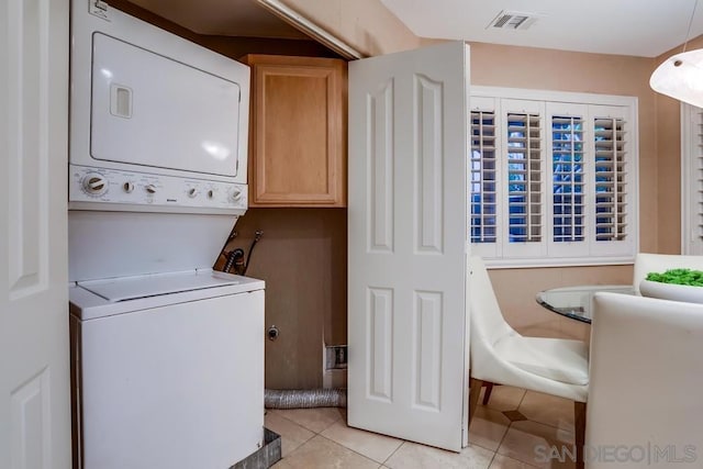 laundry room featuring stacked washer and clothes dryer and light tile patterned floors