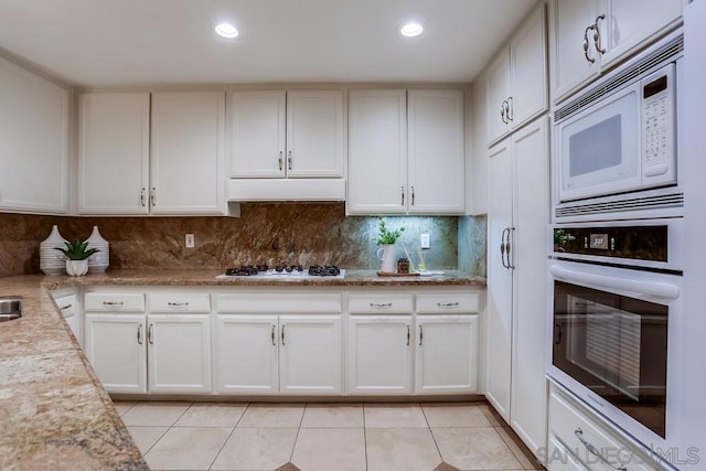 kitchen with white cabinetry, white appliances, decorative backsplash, and light tile patterned floors