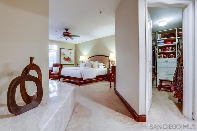 bedroom with ceiling fan, a spacious closet, and light carpet