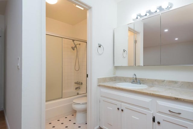 full bathroom with enclosed tub / shower combo, vanity, and toilet