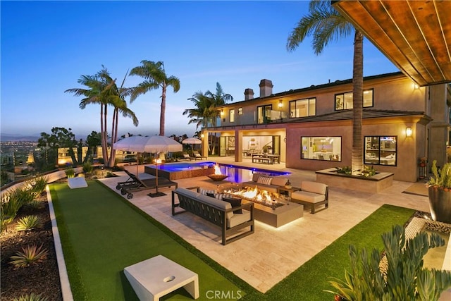 pool at dusk featuring a patio area and an outdoor living space with a fire pit