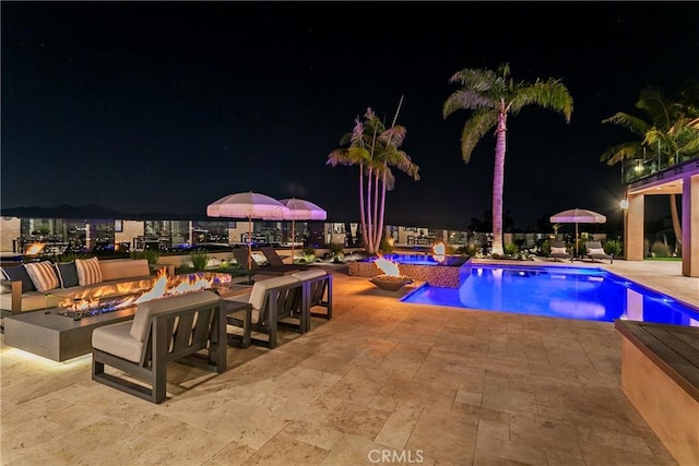 pool at twilight with an outdoor fire pit and a patio area