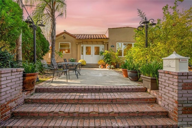 back house at dusk featuring a patio area