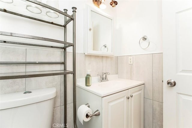 bathroom with vanity, tile walls, and toilet