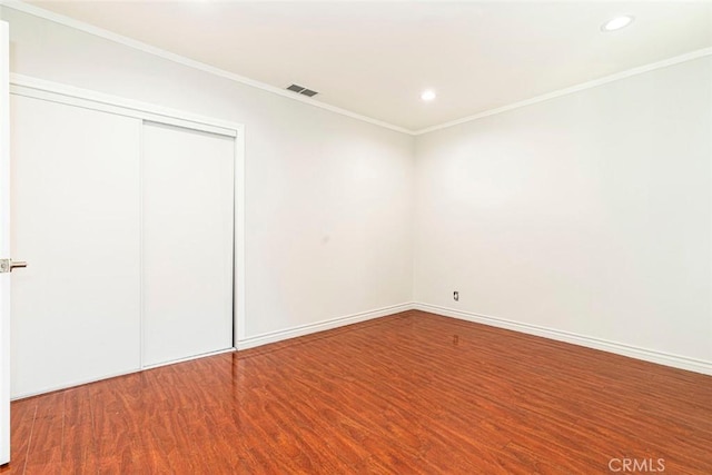 unfurnished bedroom featuring hardwood / wood-style floors, crown molding, and a closet