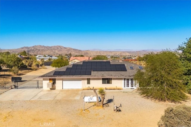 back of property with a mountain view, french doors, solar panels, and a garage