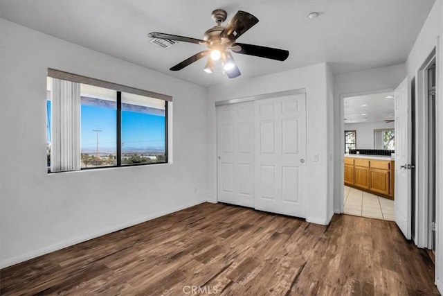 unfurnished bedroom with hardwood / wood-style floors, ceiling fan, a closet, and multiple windows