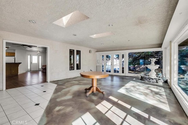 living room featuring a skylight, ceiling fan, french doors, and a healthy amount of sunlight