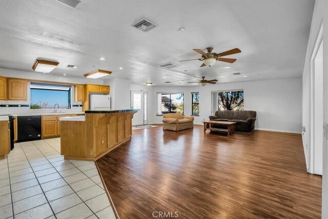 kitchen featuring dishwasher, ceiling fan, a kitchen island, light wood-type flooring, and white fridge