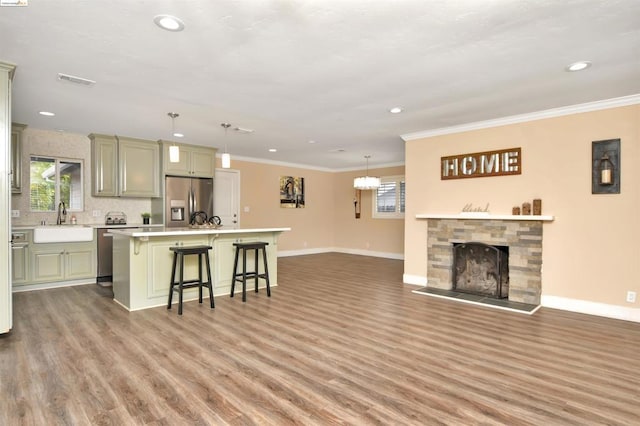 kitchen with a kitchen breakfast bar, light hardwood / wood-style floors, a fireplace, a kitchen island, and stainless steel appliances