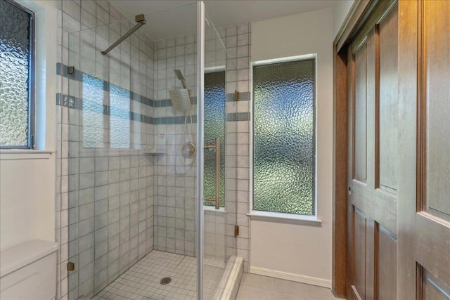 bathroom featuring a shower with door, plenty of natural light, and tile patterned flooring