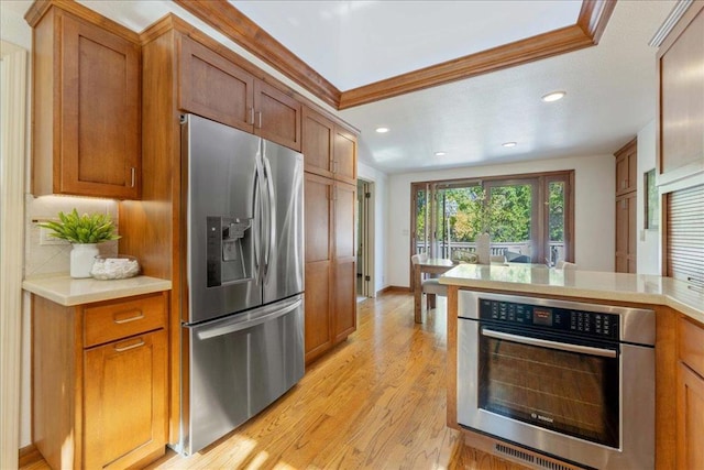 kitchen with stainless steel appliances, crown molding, and light hardwood / wood-style floors