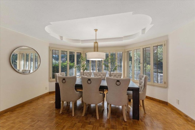 dining room featuring parquet flooring and a tray ceiling