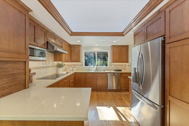 kitchen with appliances with stainless steel finishes, sink, decorative backsplash, light hardwood / wood-style floors, and kitchen peninsula