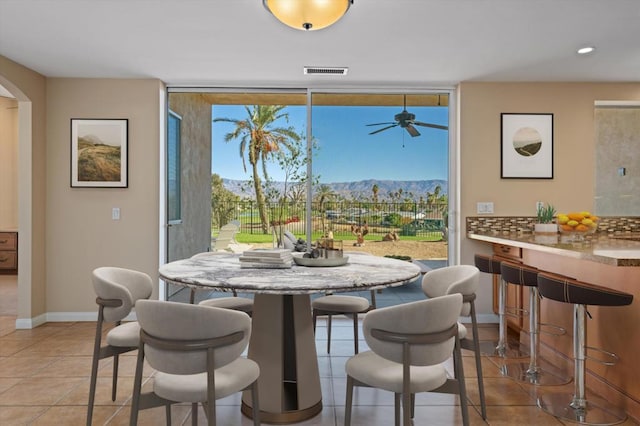 dining area featuring a mountain view, ceiling fan, and light tile patterned floors